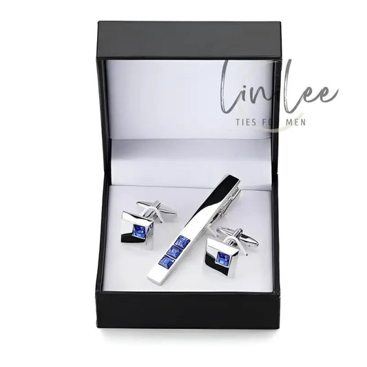 Silver cufflinks and tie clip set with blue stones in a black box.